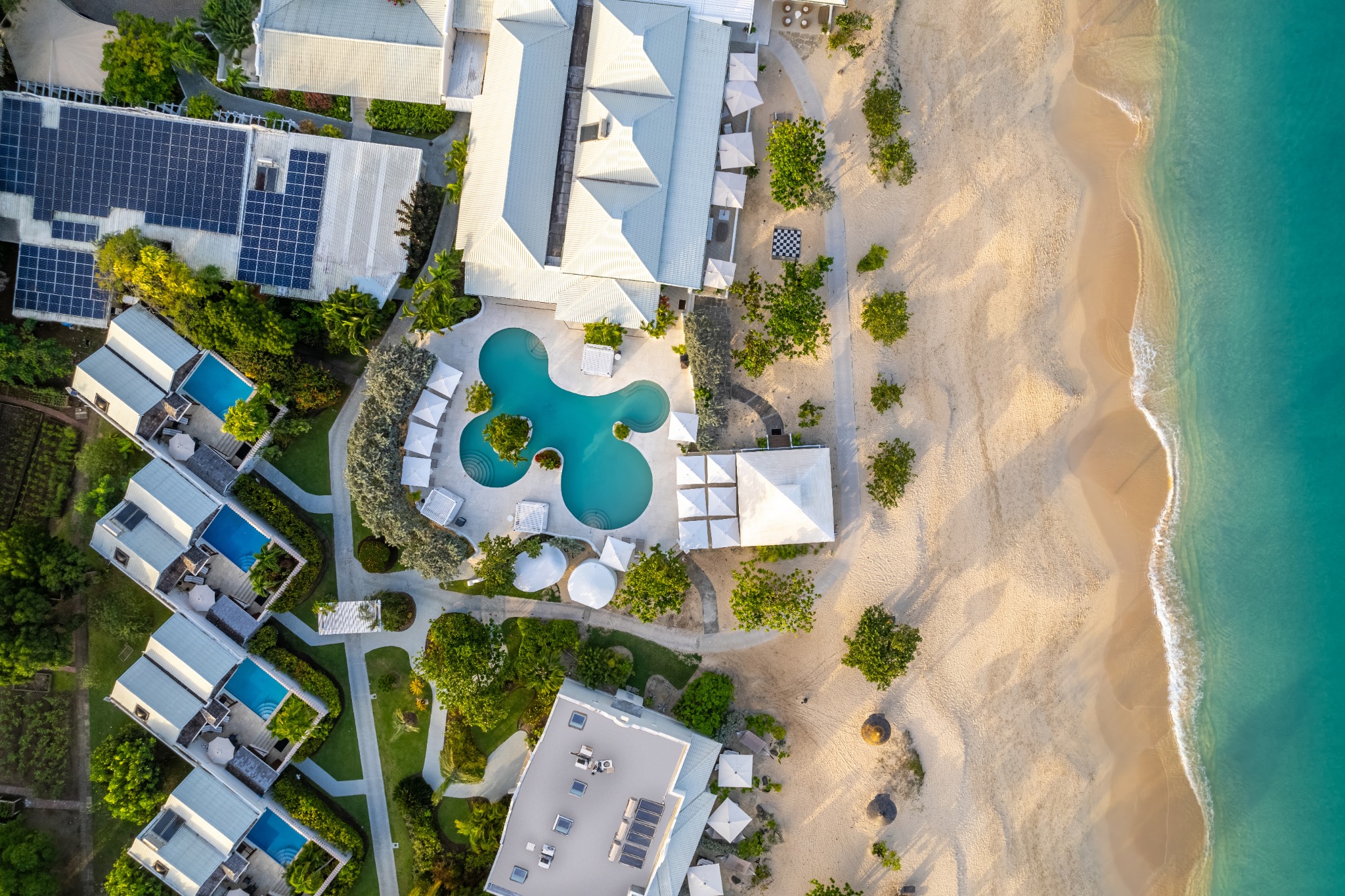 Aerial view of a beachfront resort with pools opening onto the sea