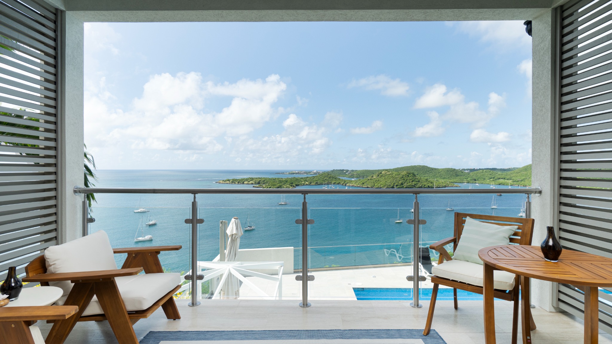 Private furnished balcony framing a wide view across a sheltered Caribbean harbour