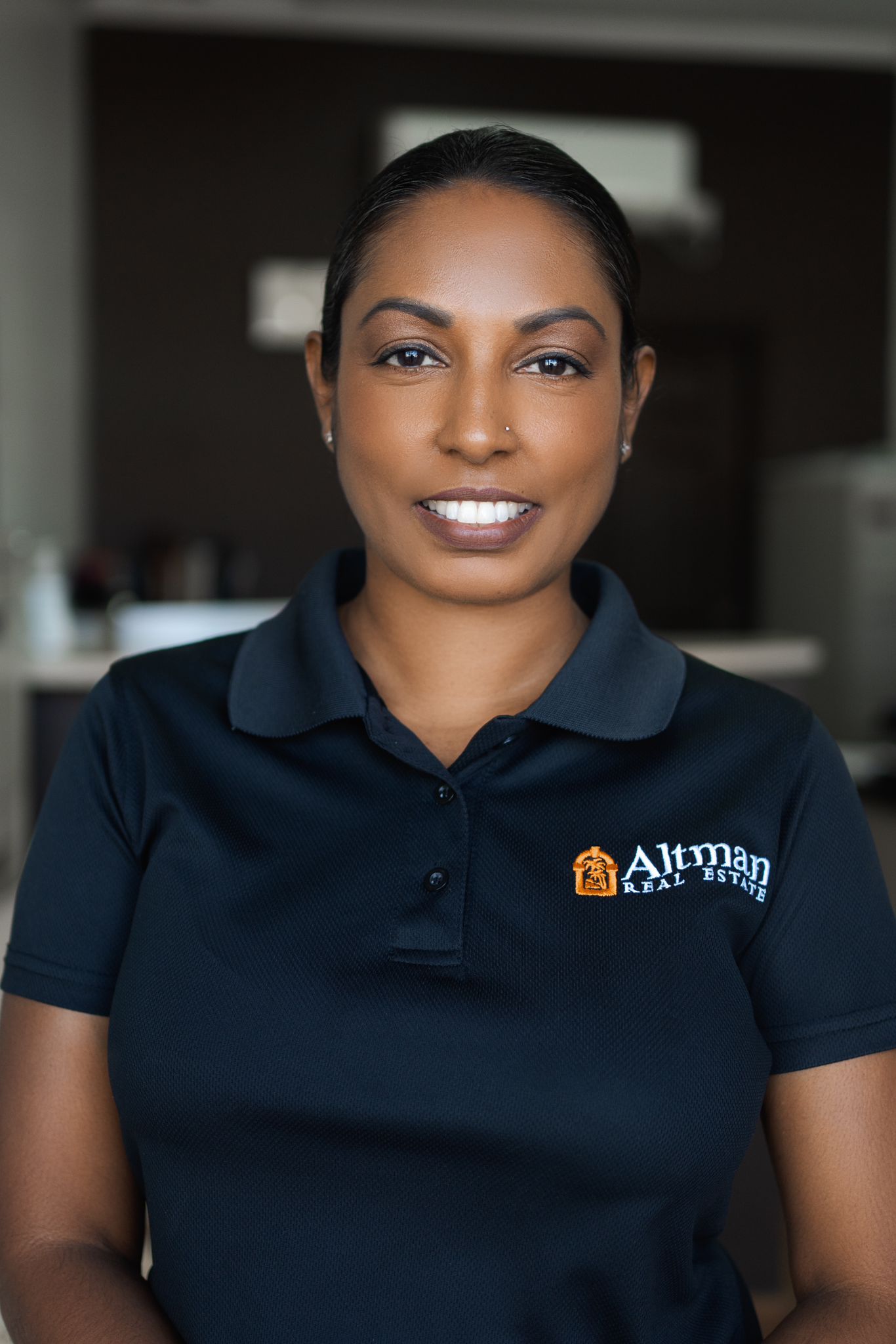 Studio-lit portrait of a staff member in a branded polo shirt against a dark background