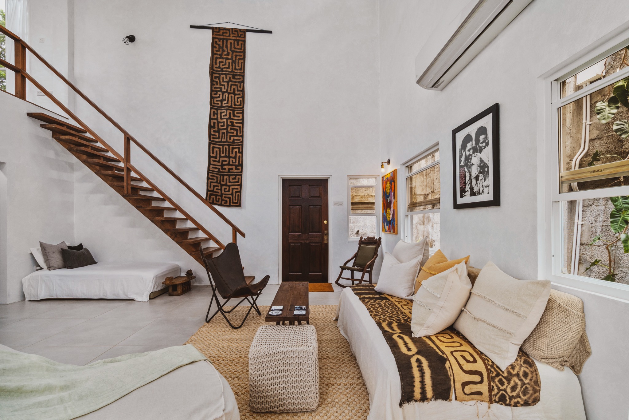 Double-height living room with a floating staircase and layered neutral furnishings