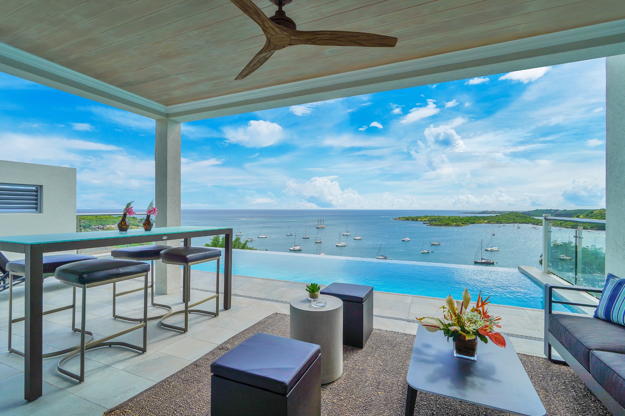 Covered outdoor lounge and bar terrace opening toward a bright Caribbean sea view